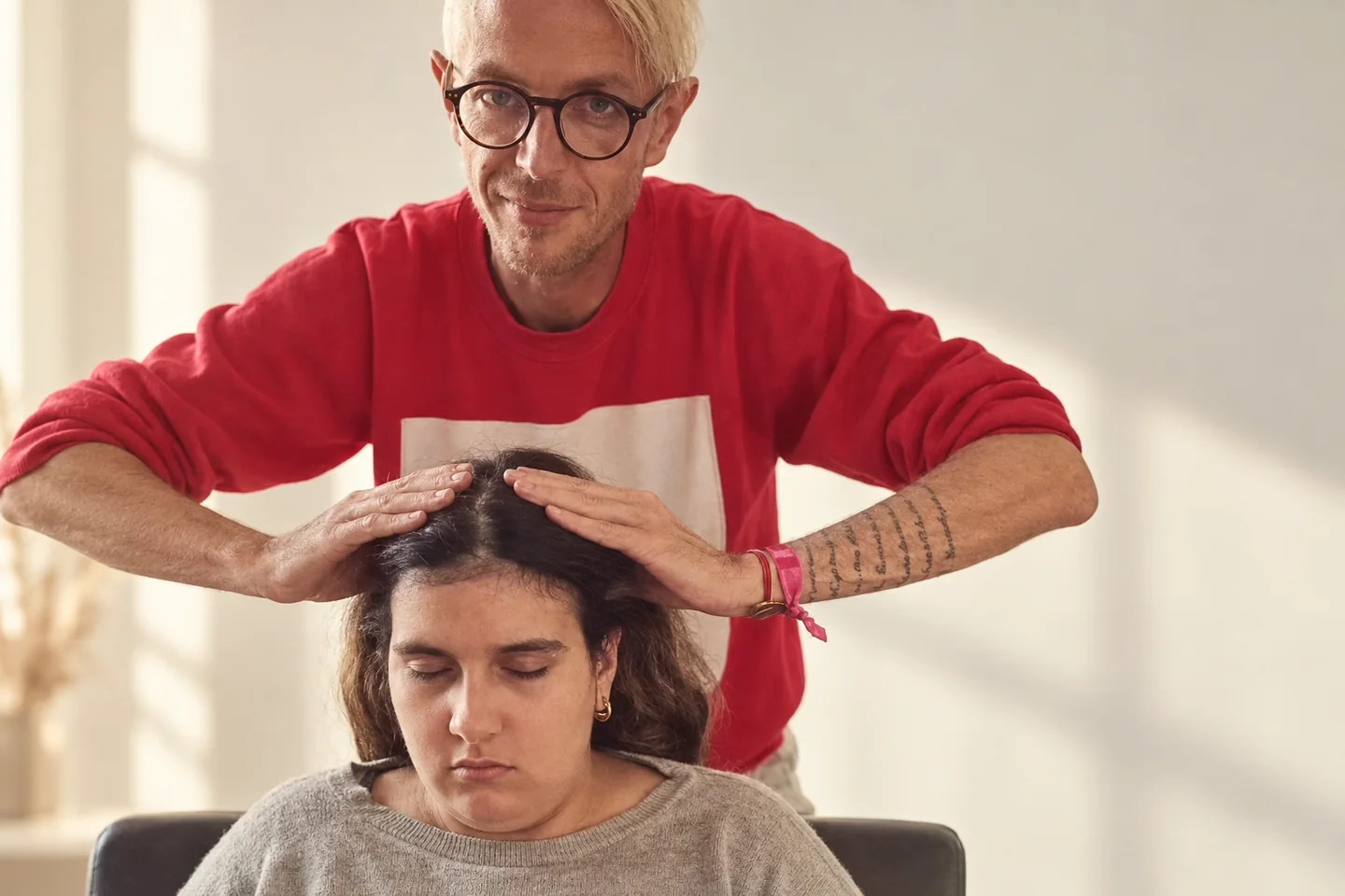 Mains posées sur la tête d’une personne aux yeux fermés lors d’un modelage.