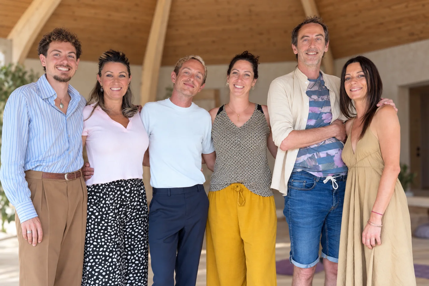 Six personnes réunies pour un portrait de groupe dans un décor en bois.