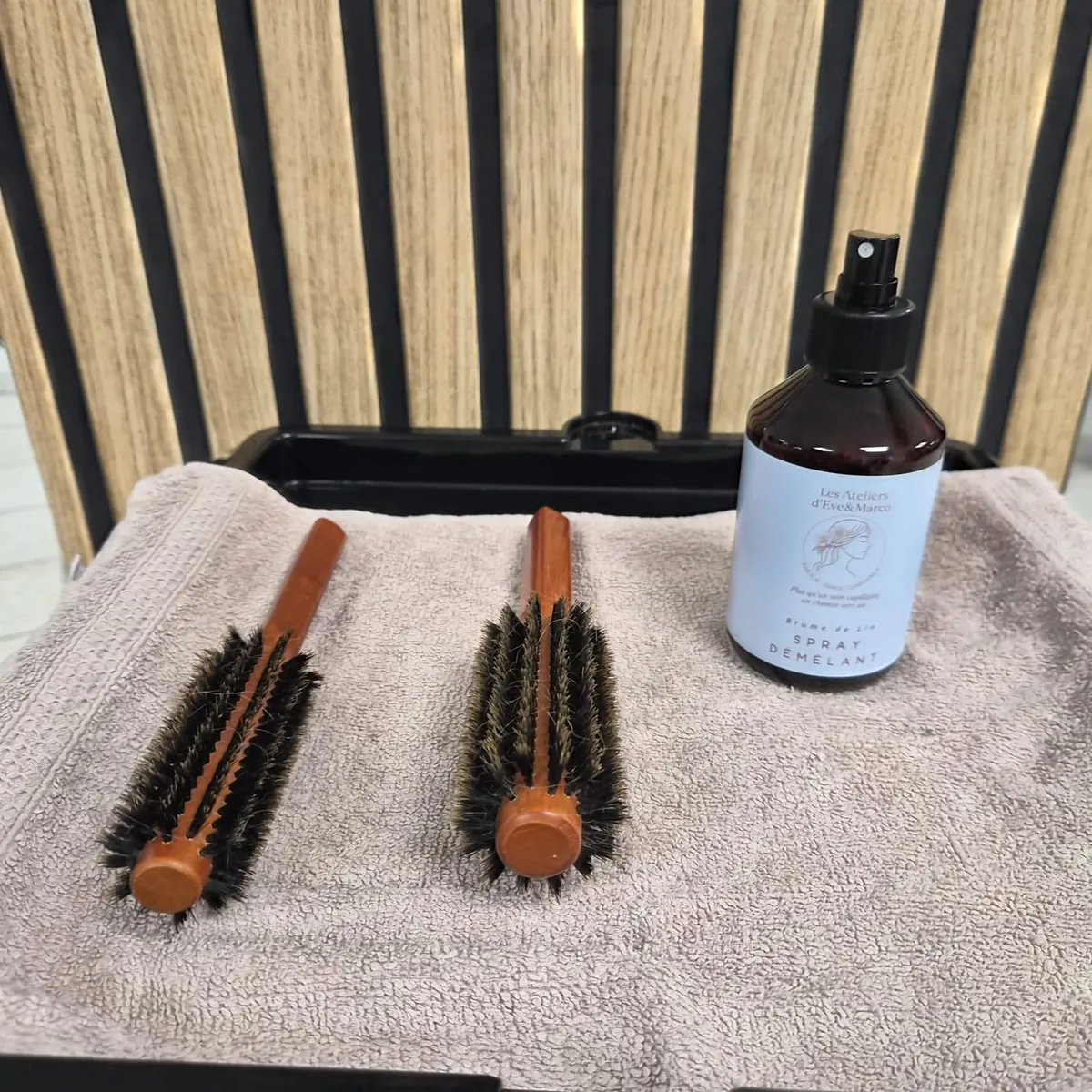 Deux brosses en bois et le spray démêlant Brume de Lin disposés sur une serviette.
