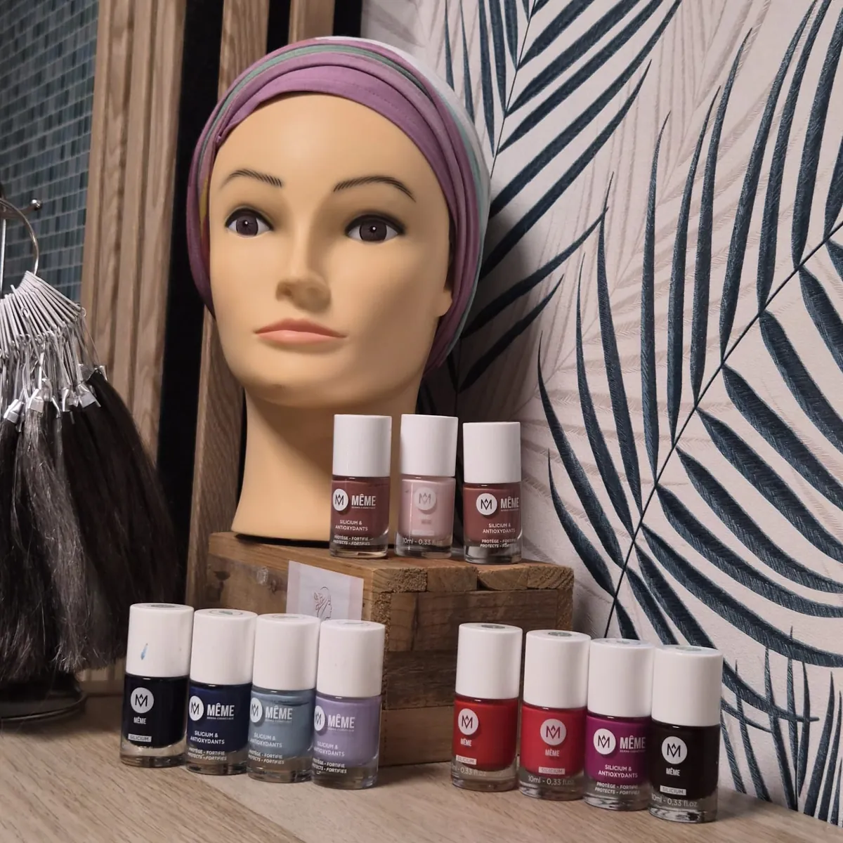 Vernis MÊME de différentes couleurs devant une tête de présentation portant un turban mauve et gris.
