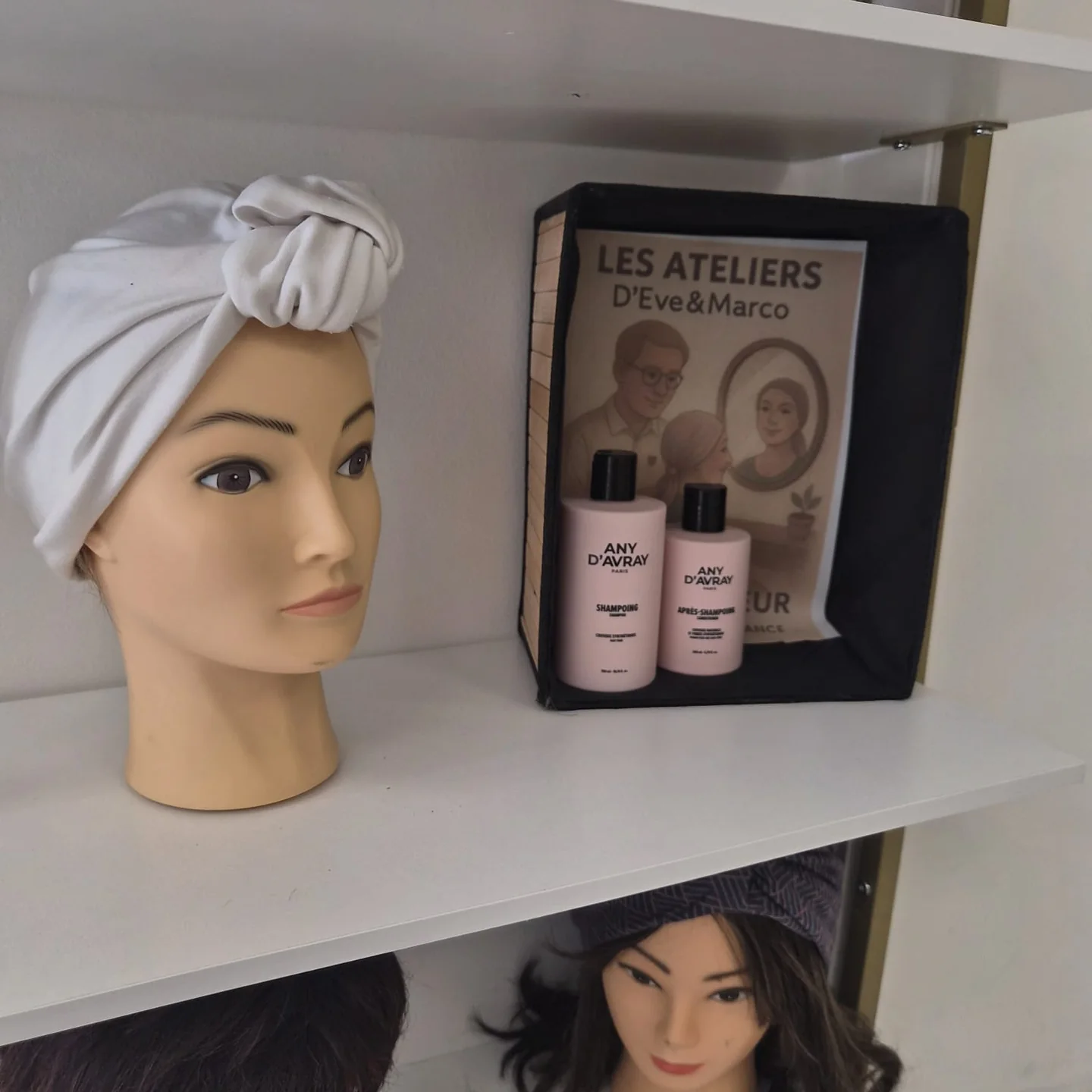Turban gris sur une tête de présentation, à côté de produits capillaires.