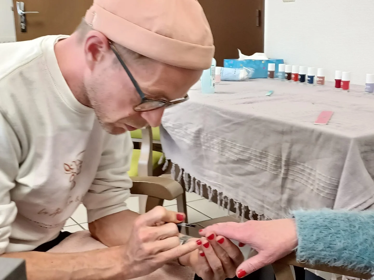Benjamin Froidure applique du vernis sur les ongles d’une personne.