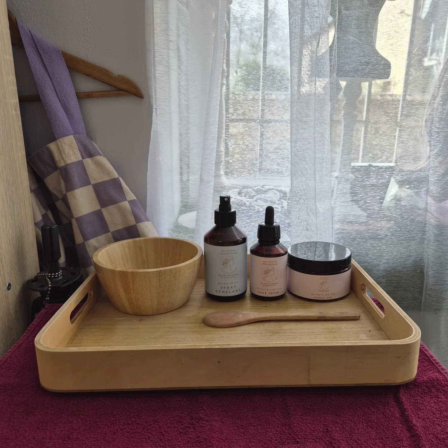 Bol en bois, spatule et produits capillaires disposés sur un plateau.