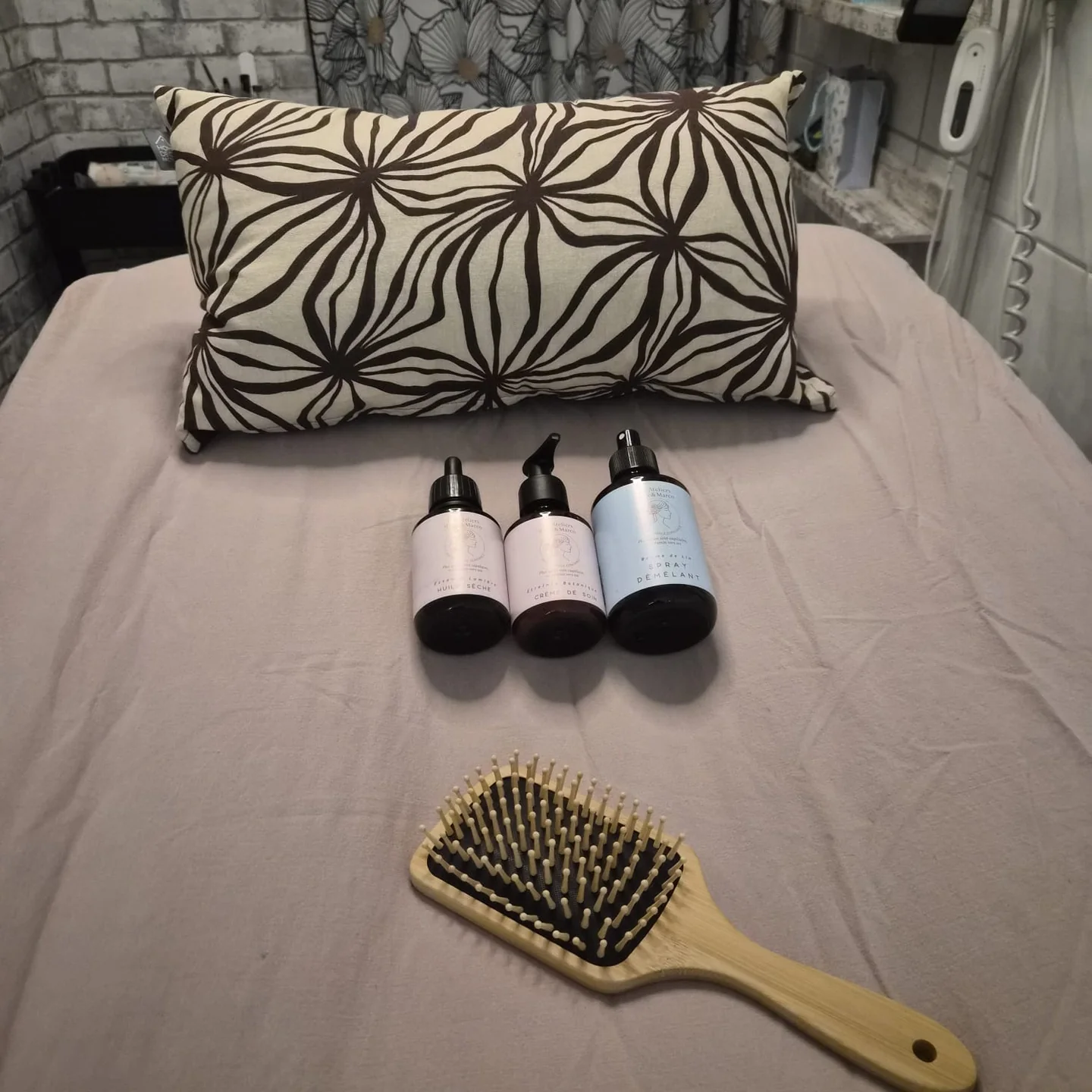 Coussin, brosse et trois flacons préparés sur une table de soin.
