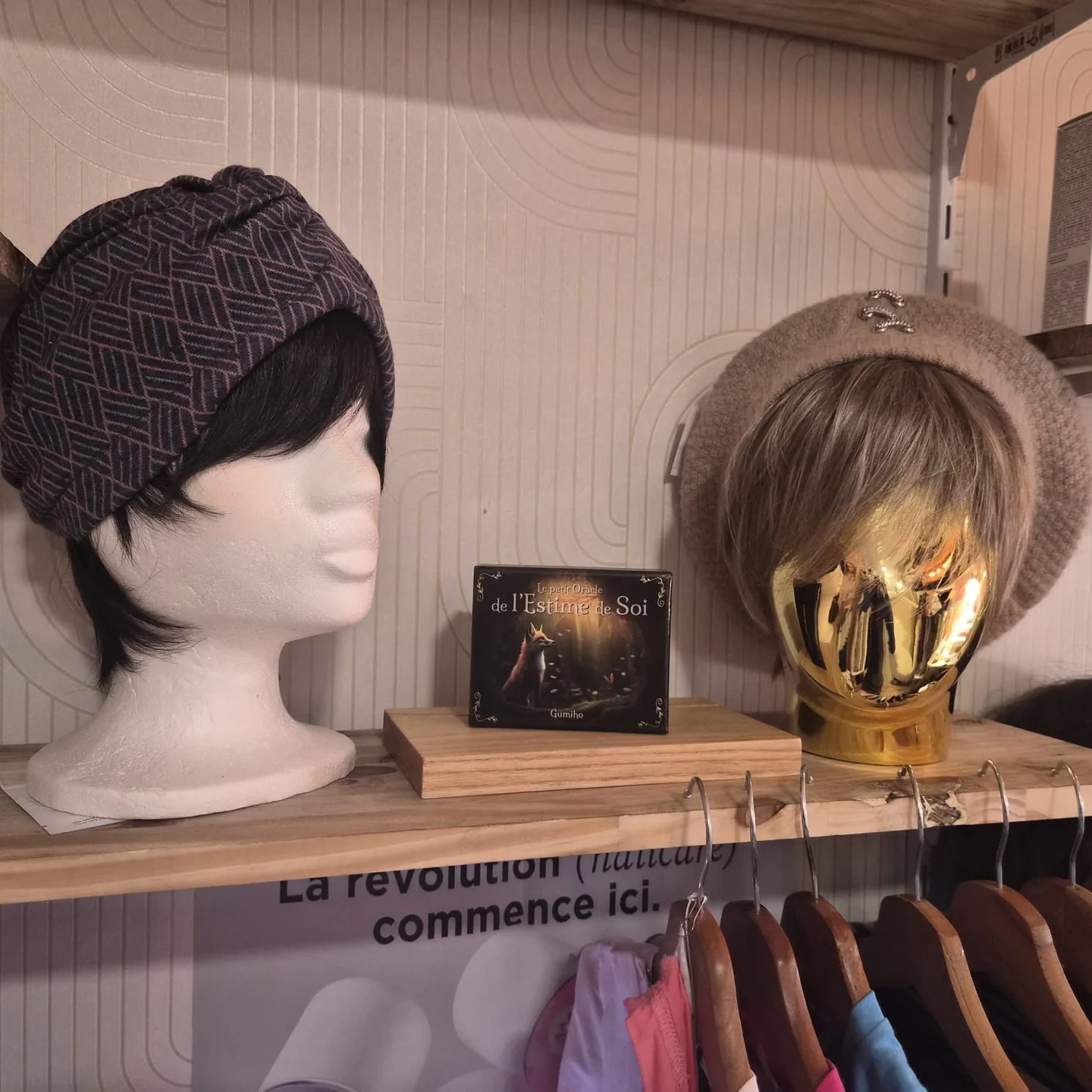 Bonnet noir et prothèse capillaire courte présentés côte à côte sur une étagère.
